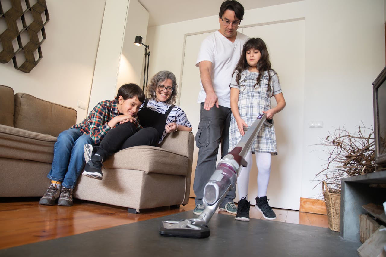 A family sharing a fun moment while vacuuming together in the living room.